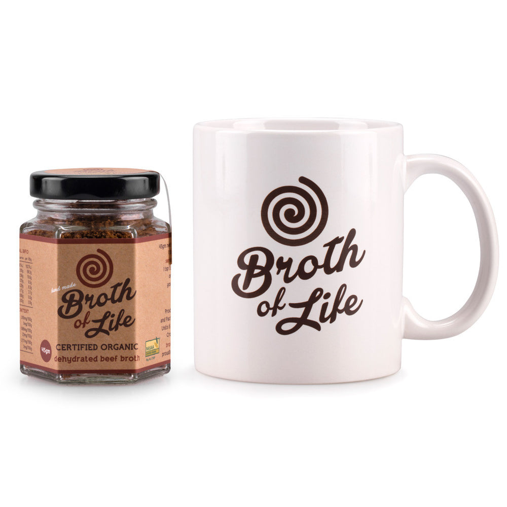 Small 45 gram jar of organic beef bone broth and a white Broth of Life ceramic coffee mug