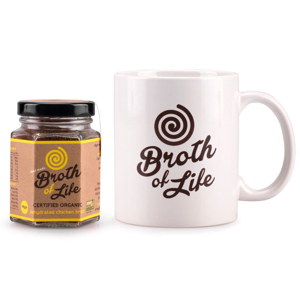 Small 45 gram jar of organic chicken bone broth and a white Broth of Life ceramic coffee mug